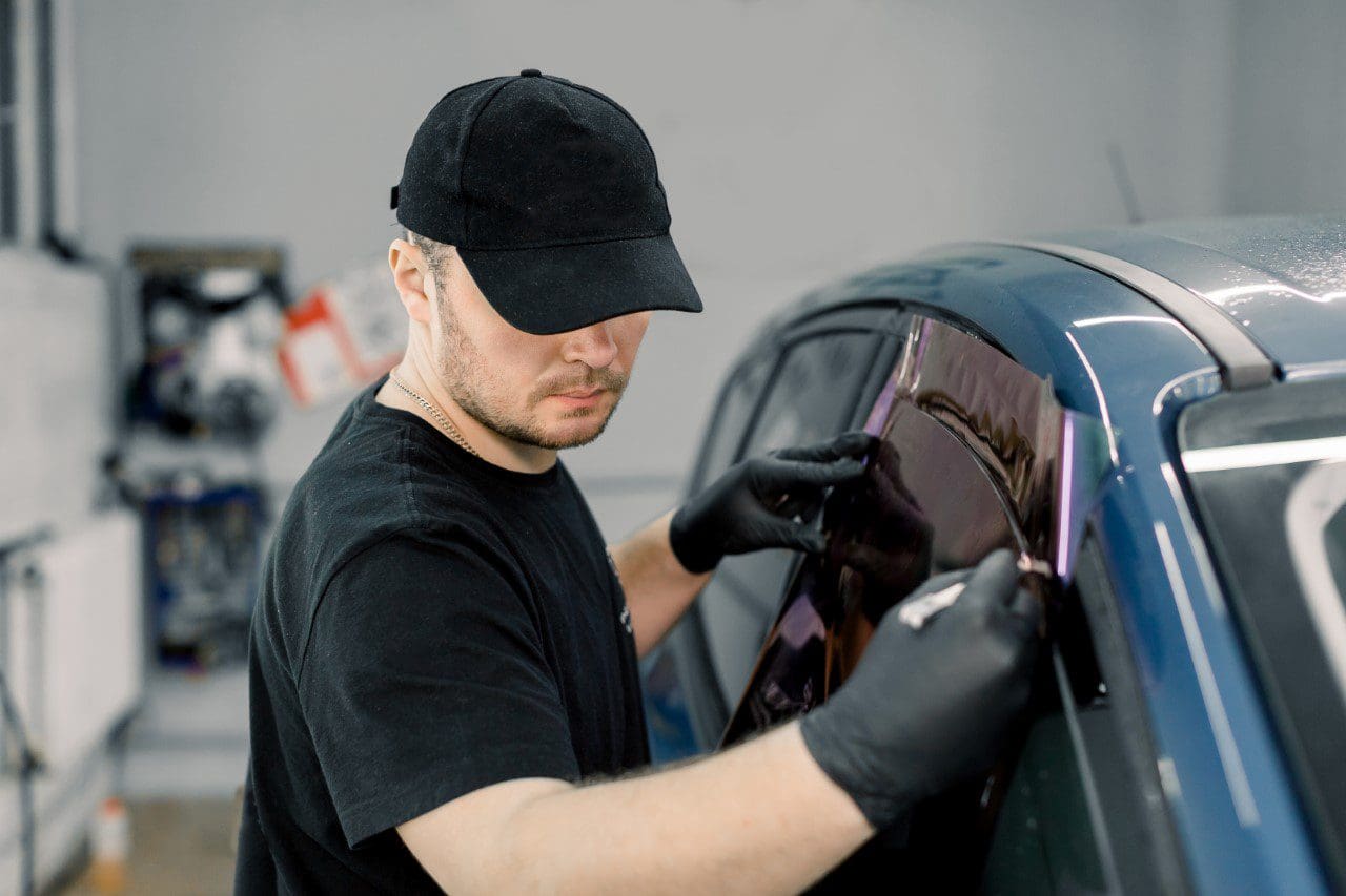 Man installing window tint on car.