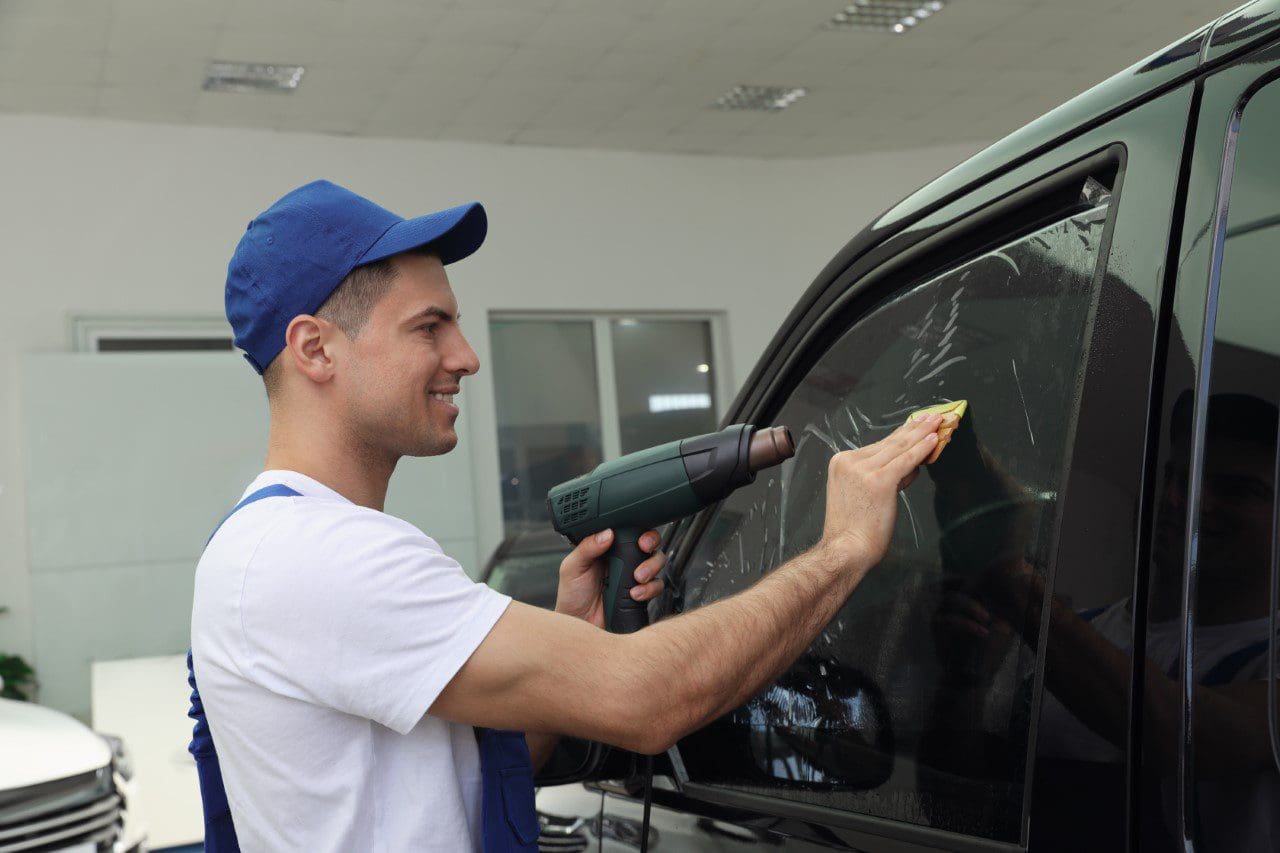 Man installing window tint on car.